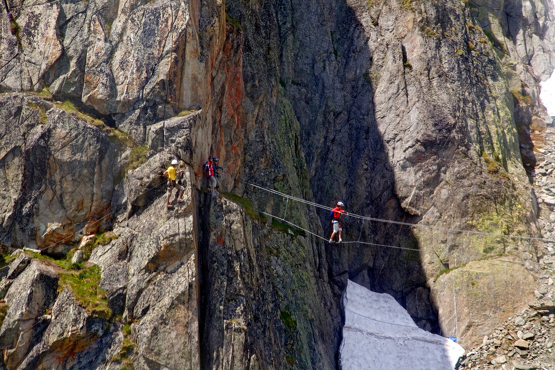 Tourist walking on tight rope while crossing valley