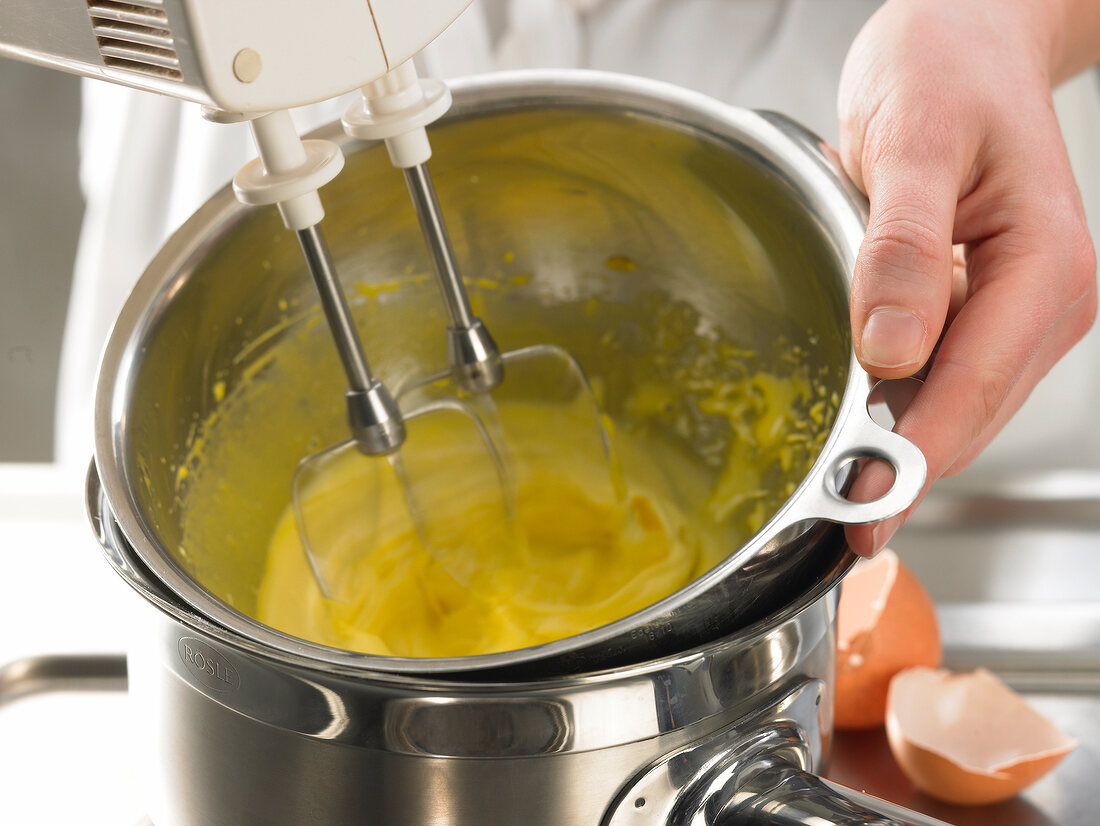 Close-up of mixing batter in bowl with hand mixer while preparing biersabayon