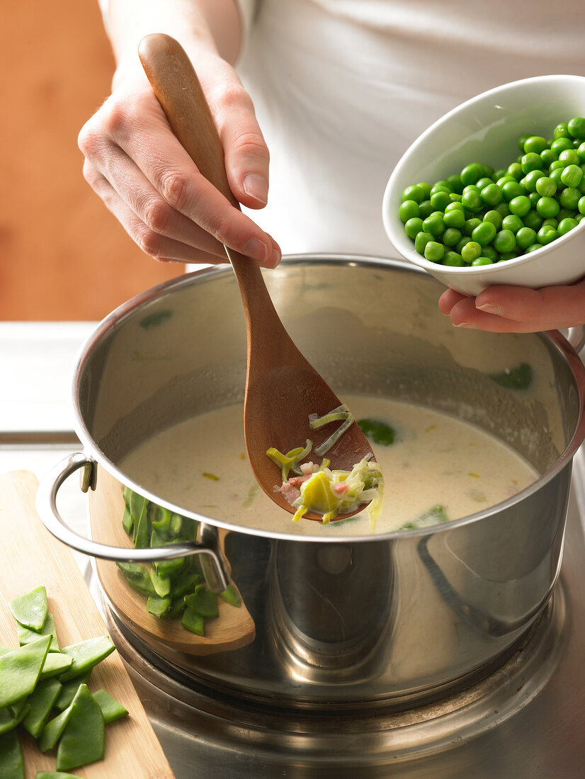 Adding peas and pea pods to German dish in cooking pot, step 1