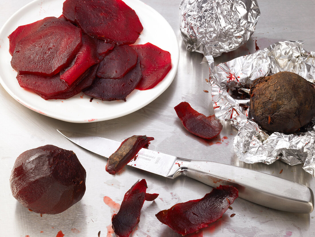 Slices of beetroot on plate beside whole peeled beetroot and knife
