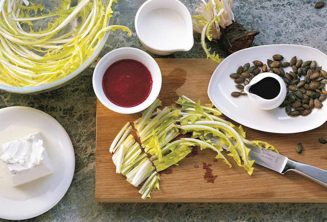 Preparing fresh salad with marinade pine nuts on wooden board