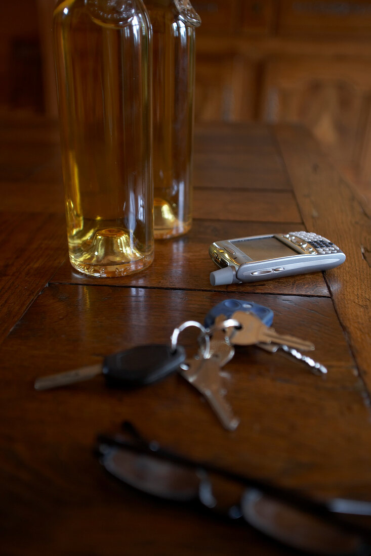 Car keys, cell phone and glasses on wooden table