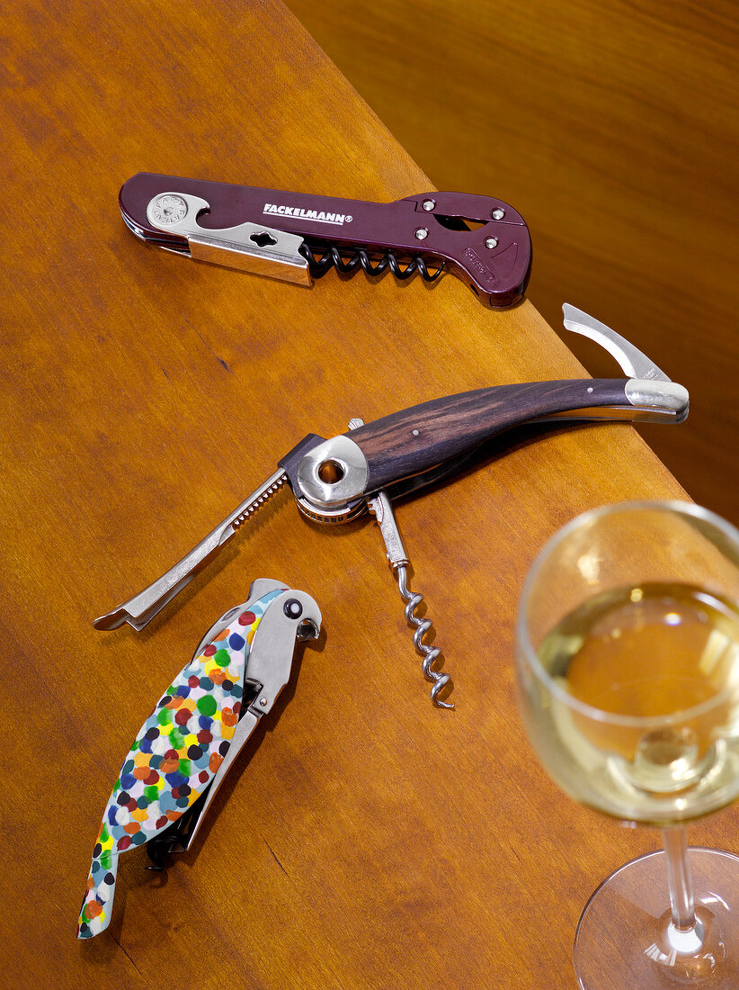 Three pocket corkscrew beside wine glass