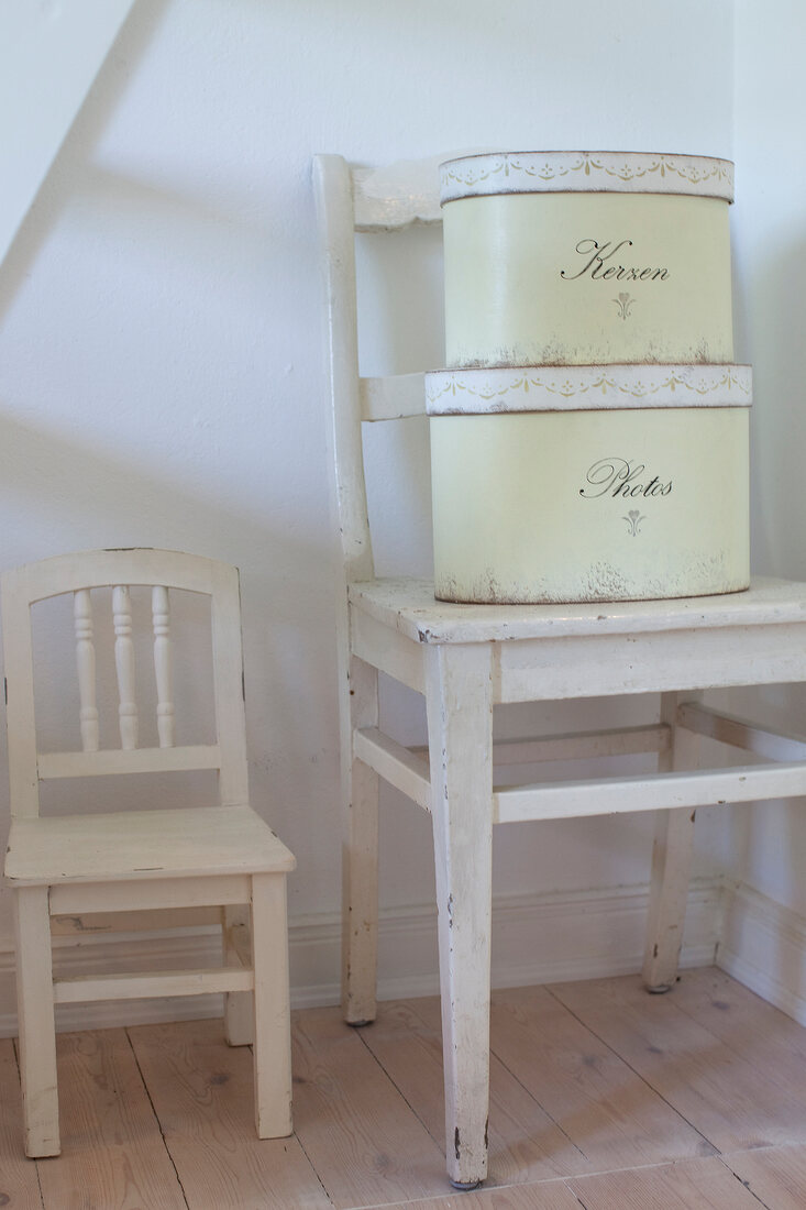White chair with two antique tin cans on white stool