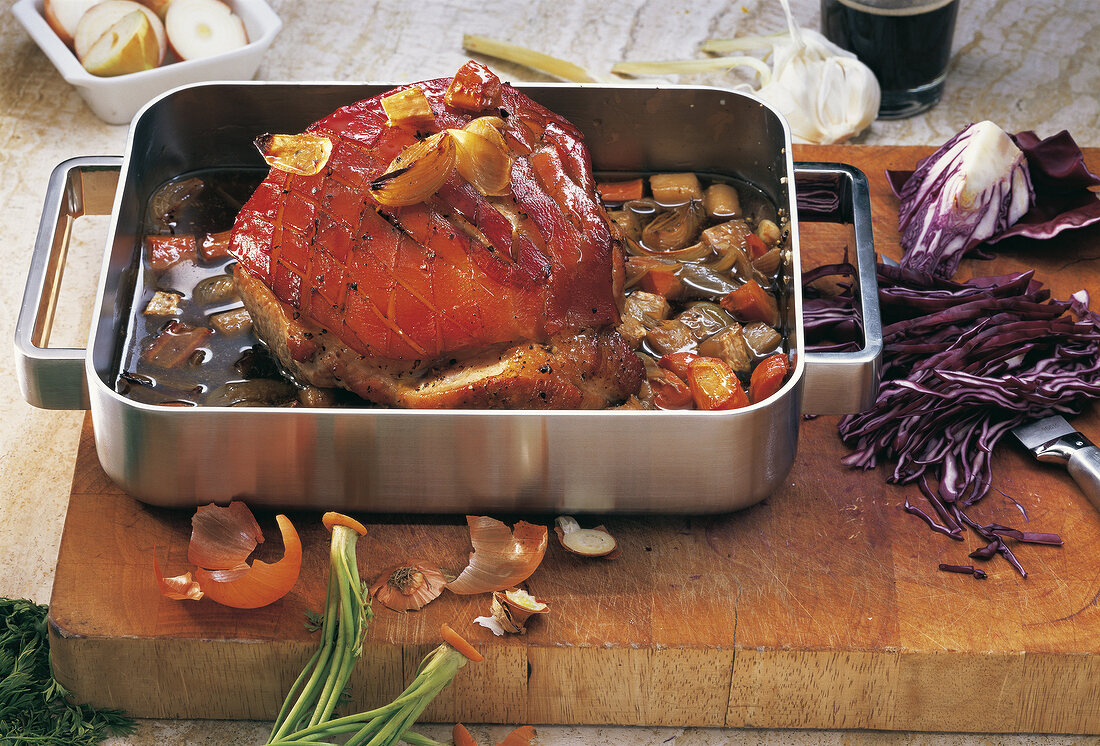 Meat being prepared with braised vegetable in baking dish