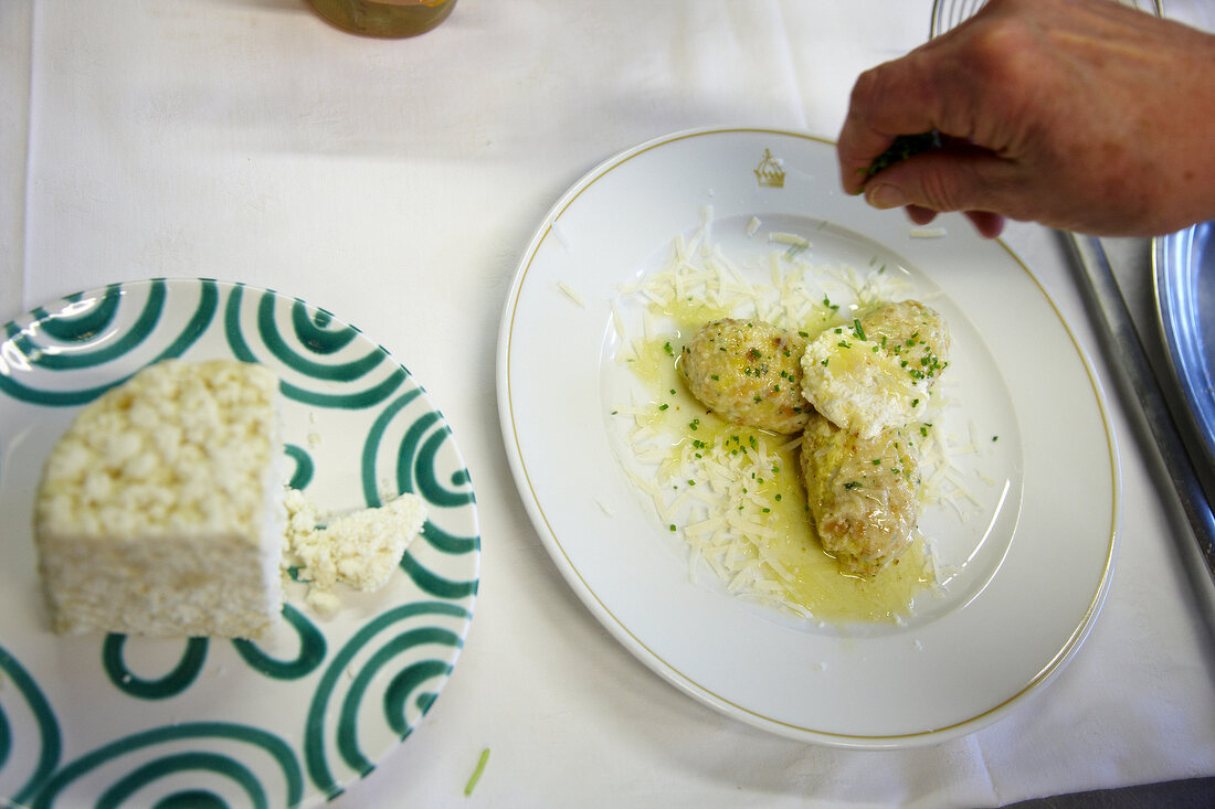 Graukasnocken with brown butter being garnished on plate