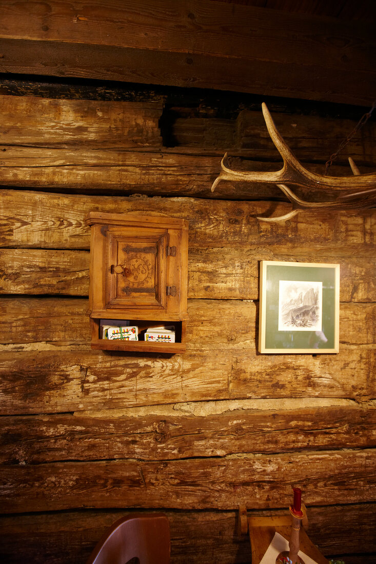 Wooden wall in mountain hut with small cupboard and picture frame