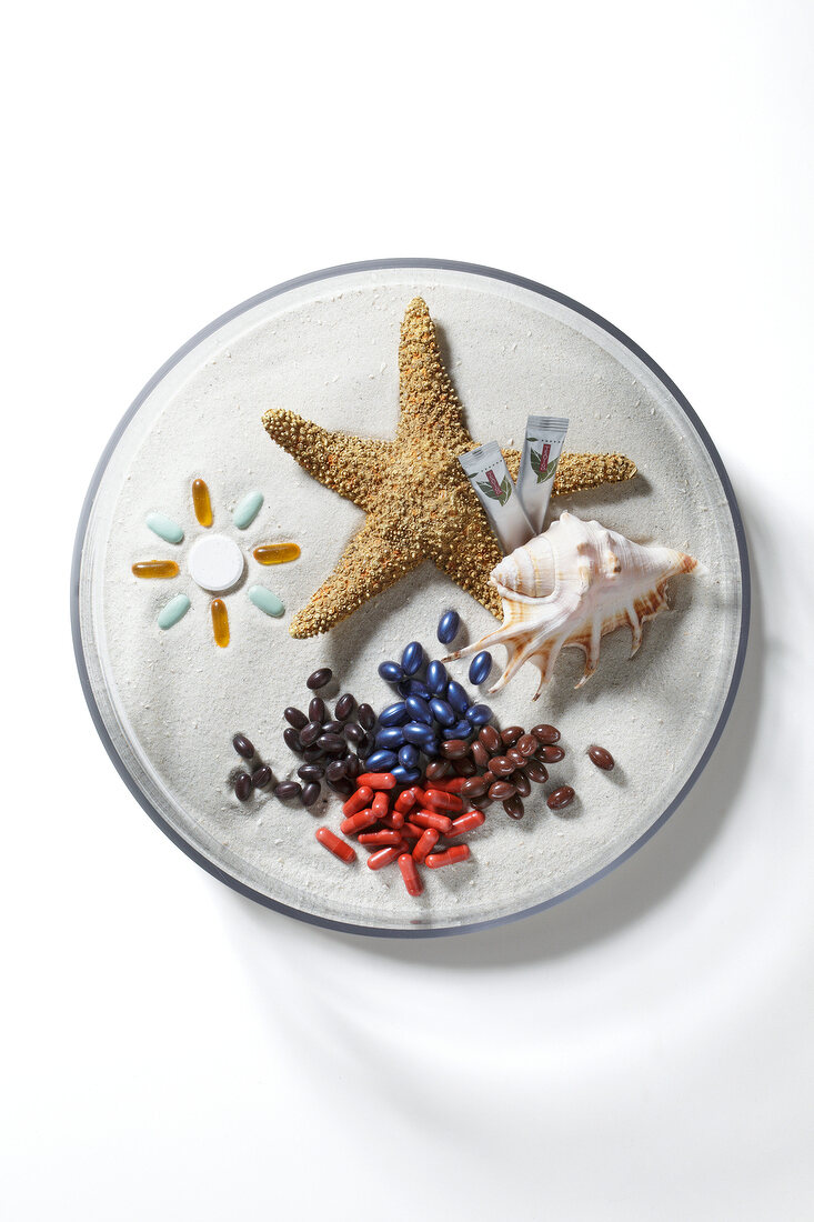 Sea shell, star fish, and multi coloured beads on white surface
