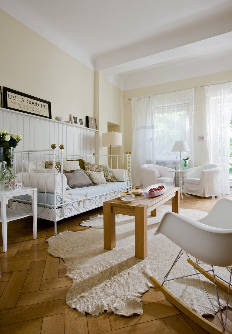 Swedish style living room with white iron bed, wooden table and floor lamp
