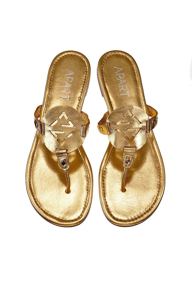 Close-up of golden colour toe sandals on white background