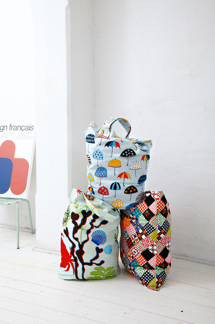 Three multi-colour patterned fabric shopping bags on wooden floor