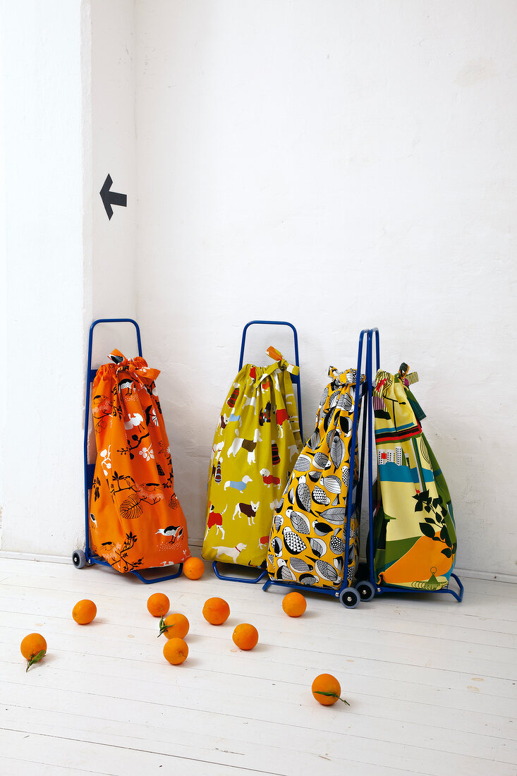 Four shopping bags on wheels with oranges