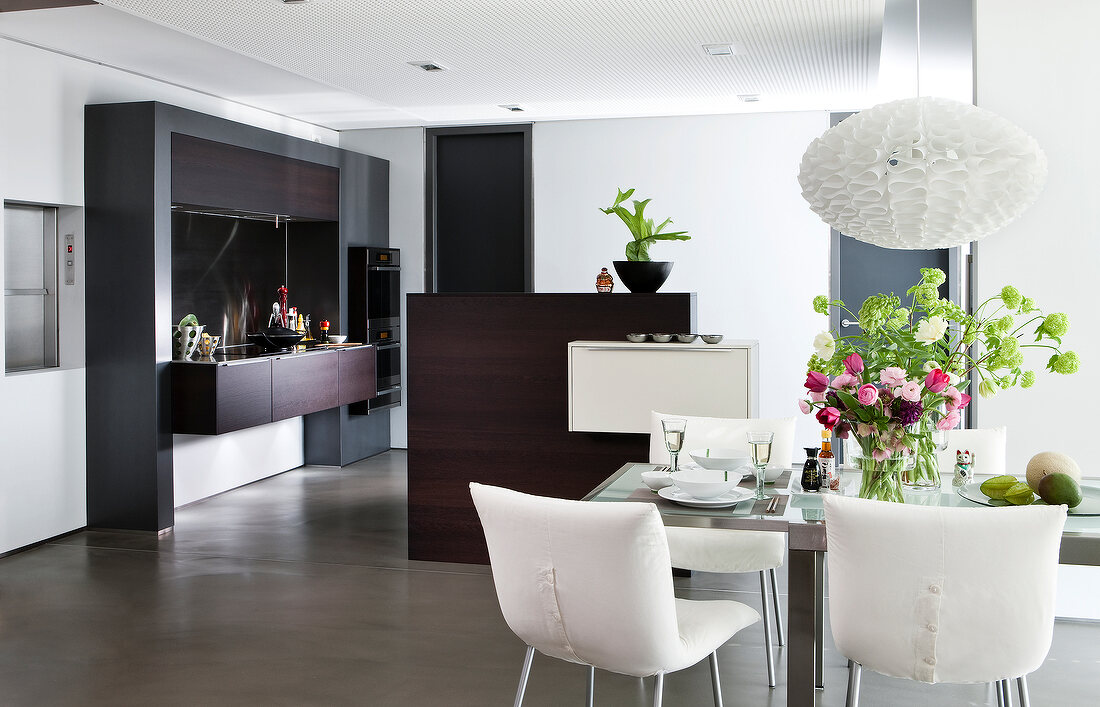 Modern kitchen in wood and stainless steel with dining table on concrete floor