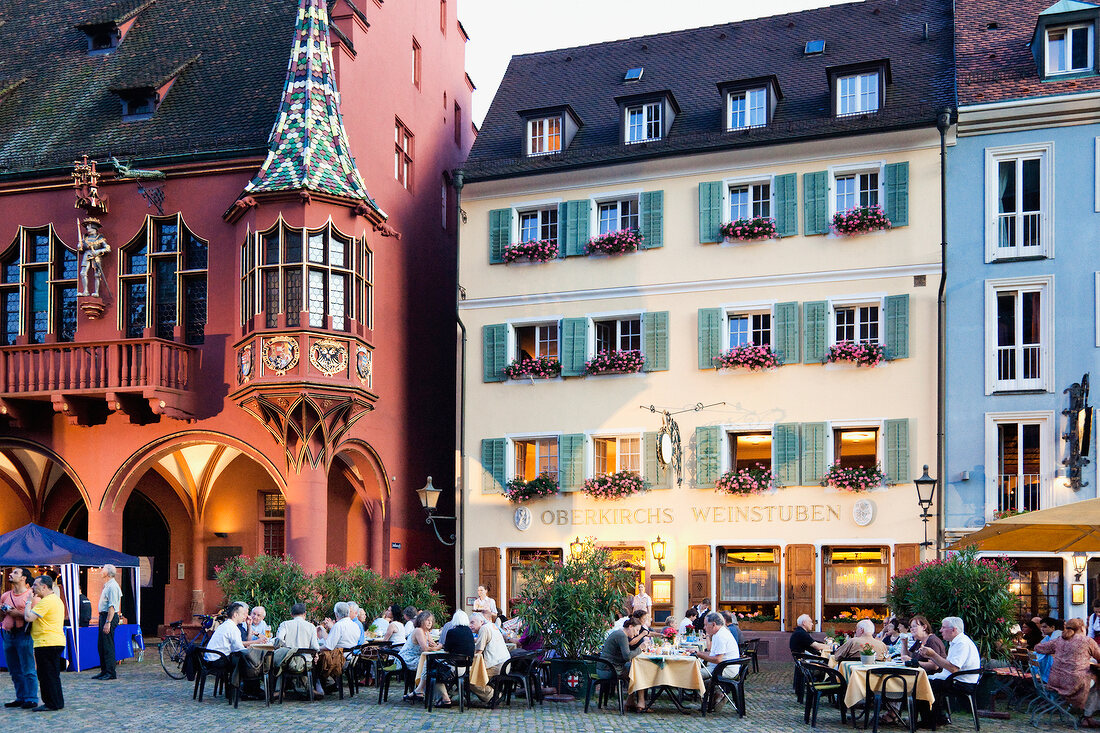 Guests sitting at table in front of Cathedral Square in Freiburg, Black Forest, Germany