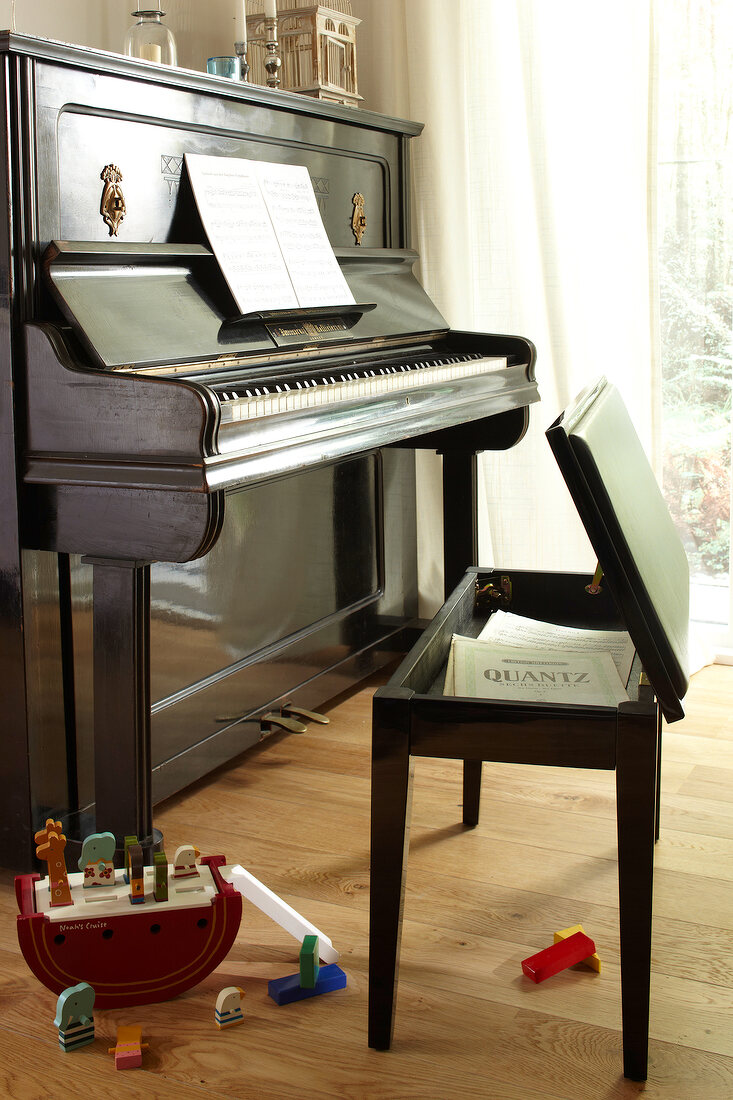 Piano and piano stool with notes on wooden floor