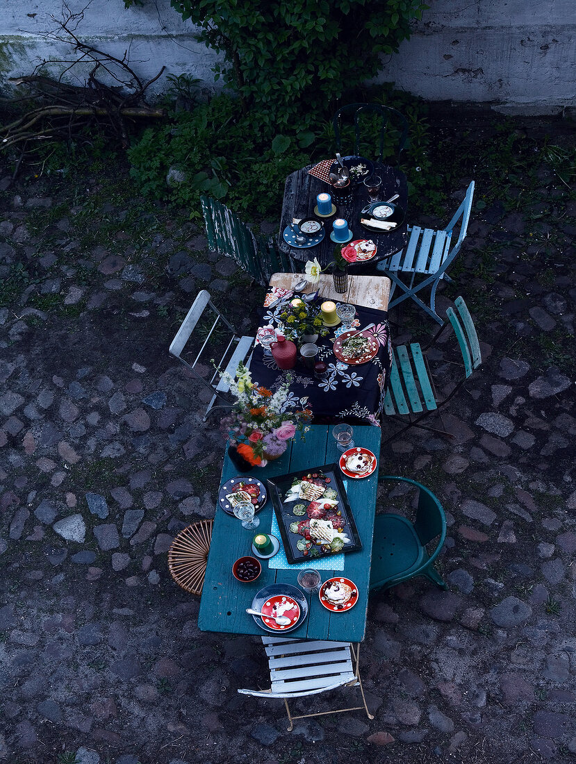 Gartentisch mit Blumen, Kerzen und leichten Sommerspeisen