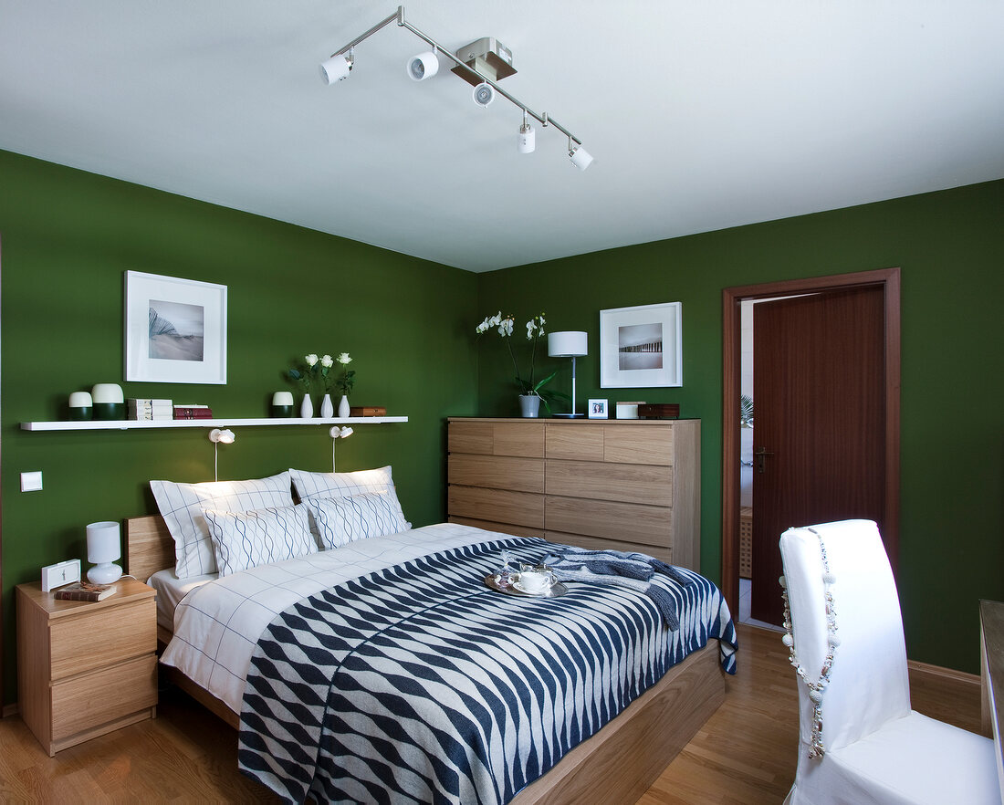 Bedroom with double bed, white cushion, side table, and chair