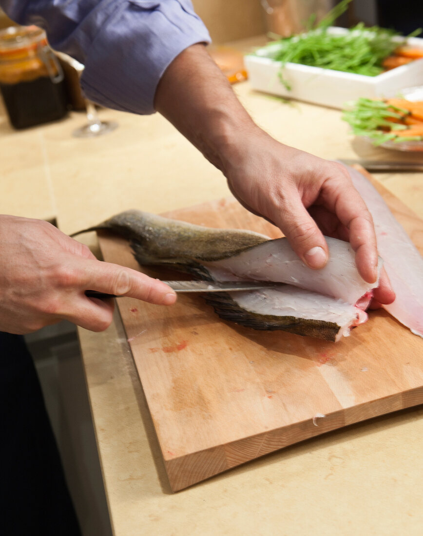 Man filleting fish with knife on cutting board