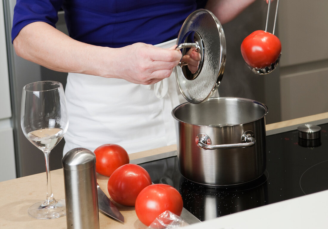 Man removing boiled tomatoes from the cooker