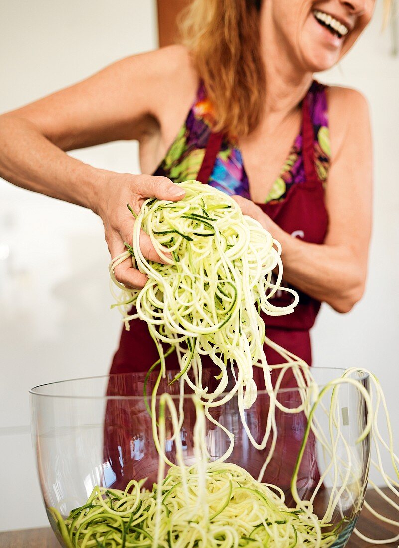 A woman preparing a vegetable spaghetti salad