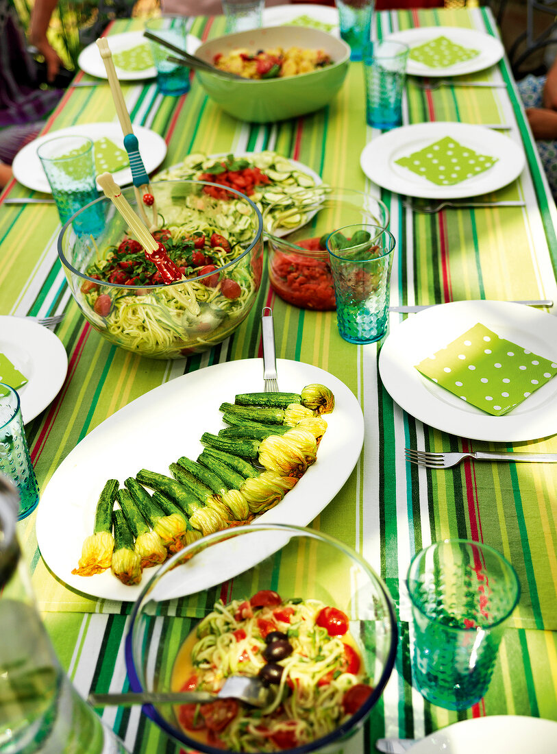 Vegetable pasta, zucchini flowers and spaghetti in bowl and serving dishes on table