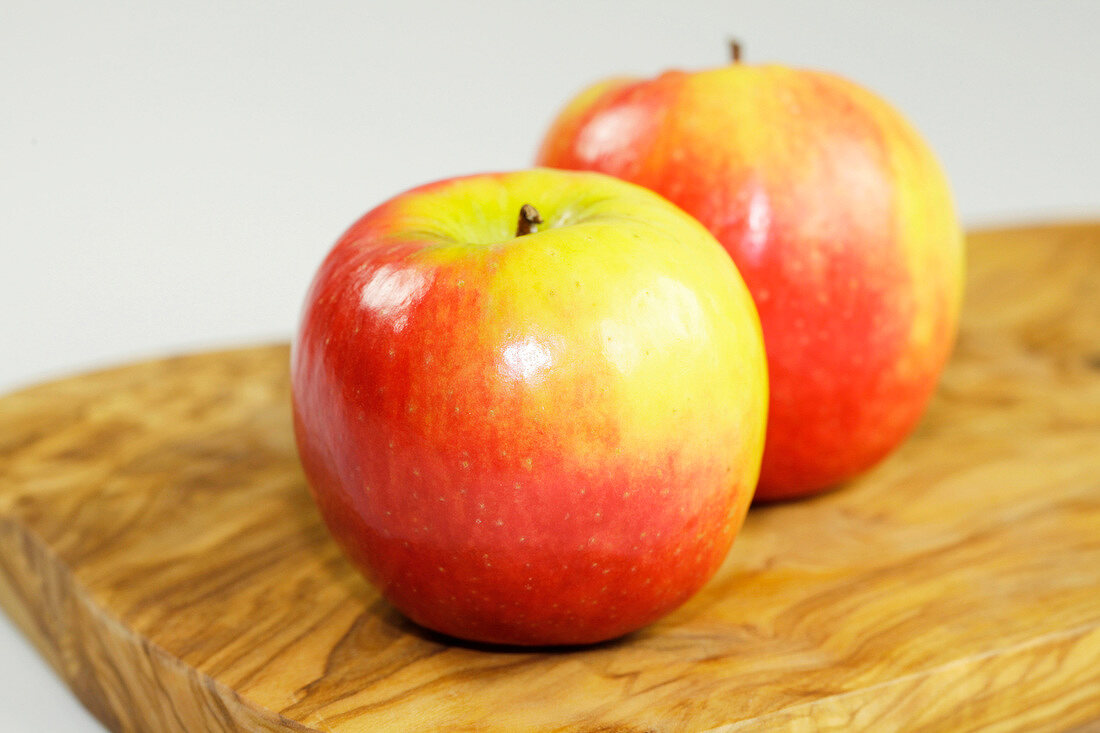 Close-up of two apples on wooden board