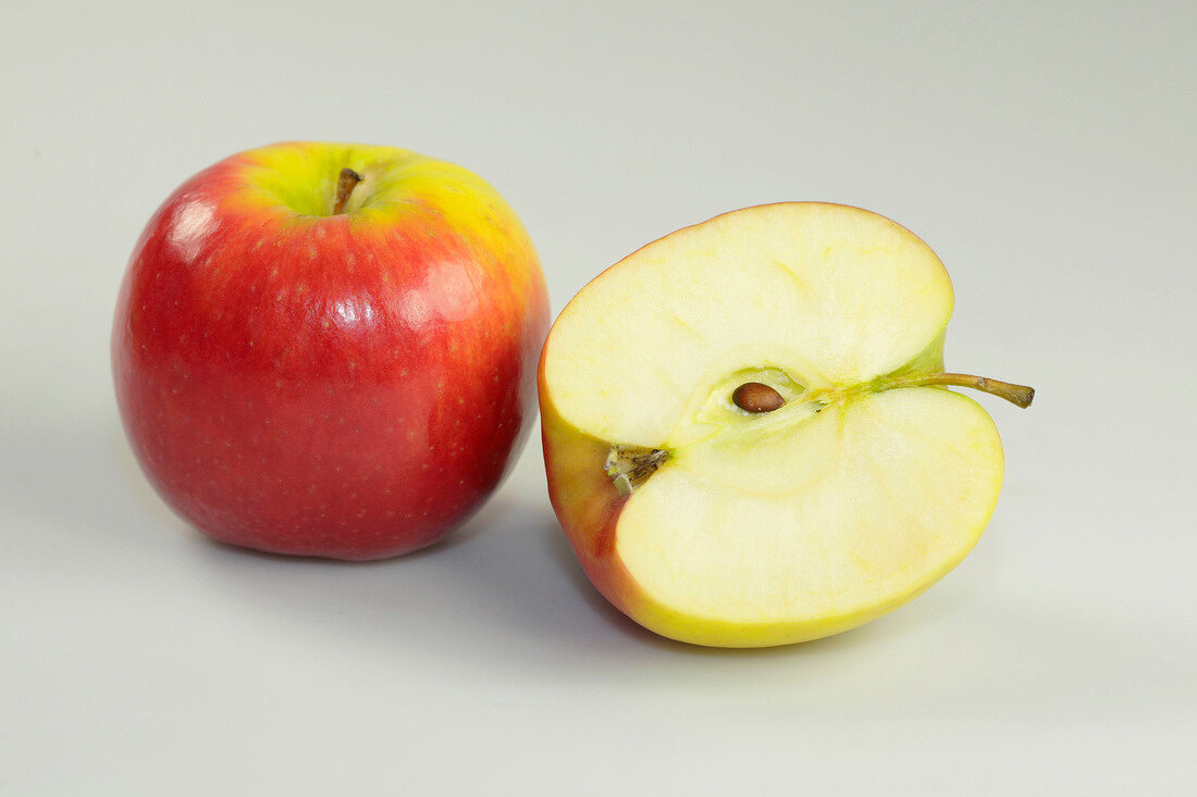 Close-up of whole and halved apple on white background