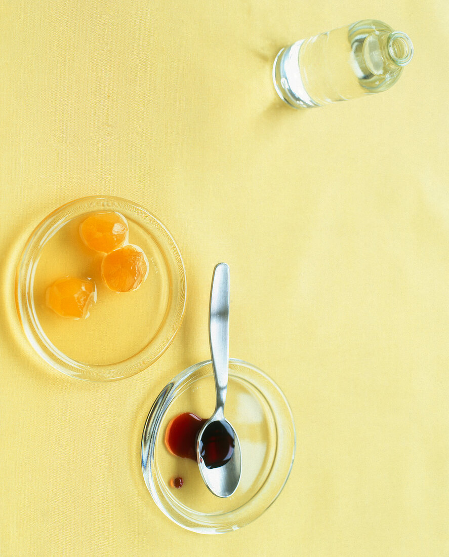 Orange blossom water bottle and plates of ginger syrup and grenadine syrup, overhead view