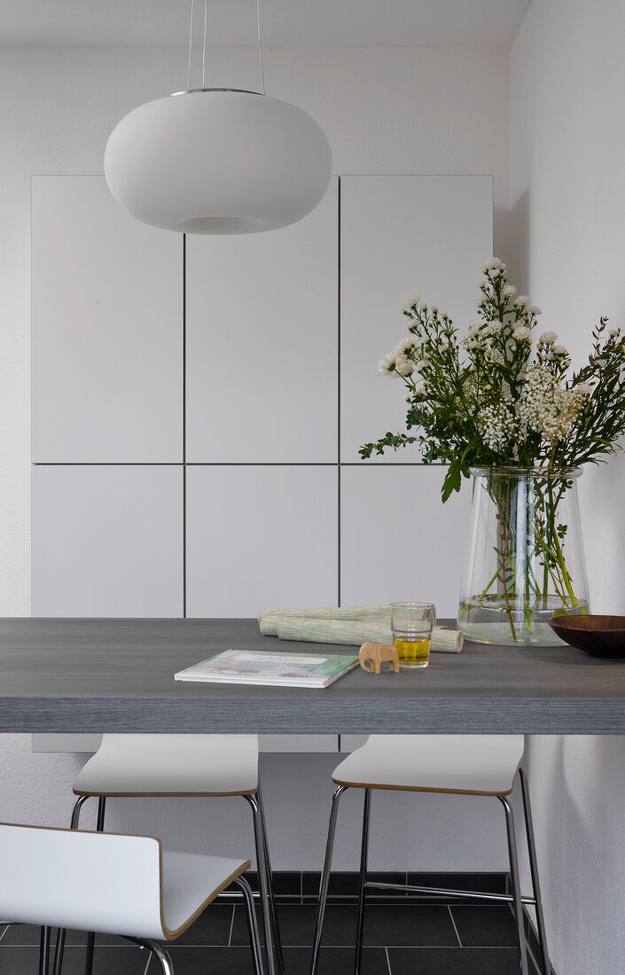 Flower vase on wall unit with chair and hanging lanterns