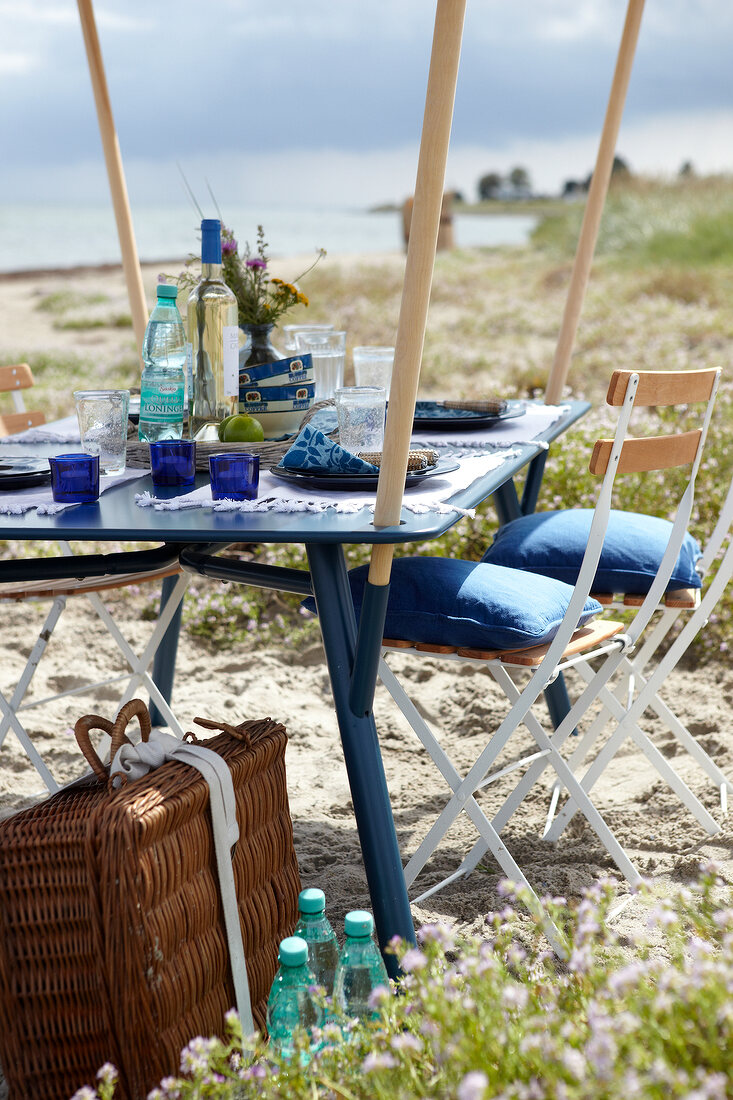 Outdoor-Möbel: Gartentisch mit aufge stecktem Sonnendach am Strand