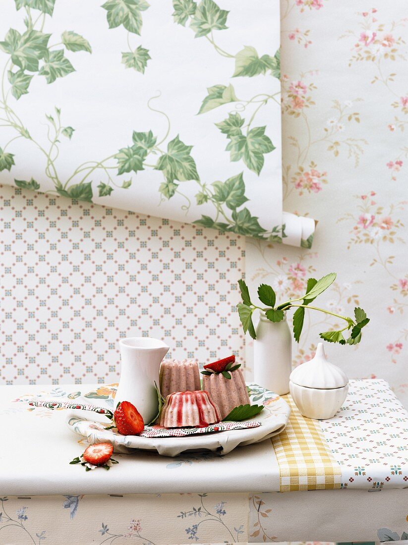 Vanilla and strawberry parfait on the table against a wall decorated with various roles of wallpaper