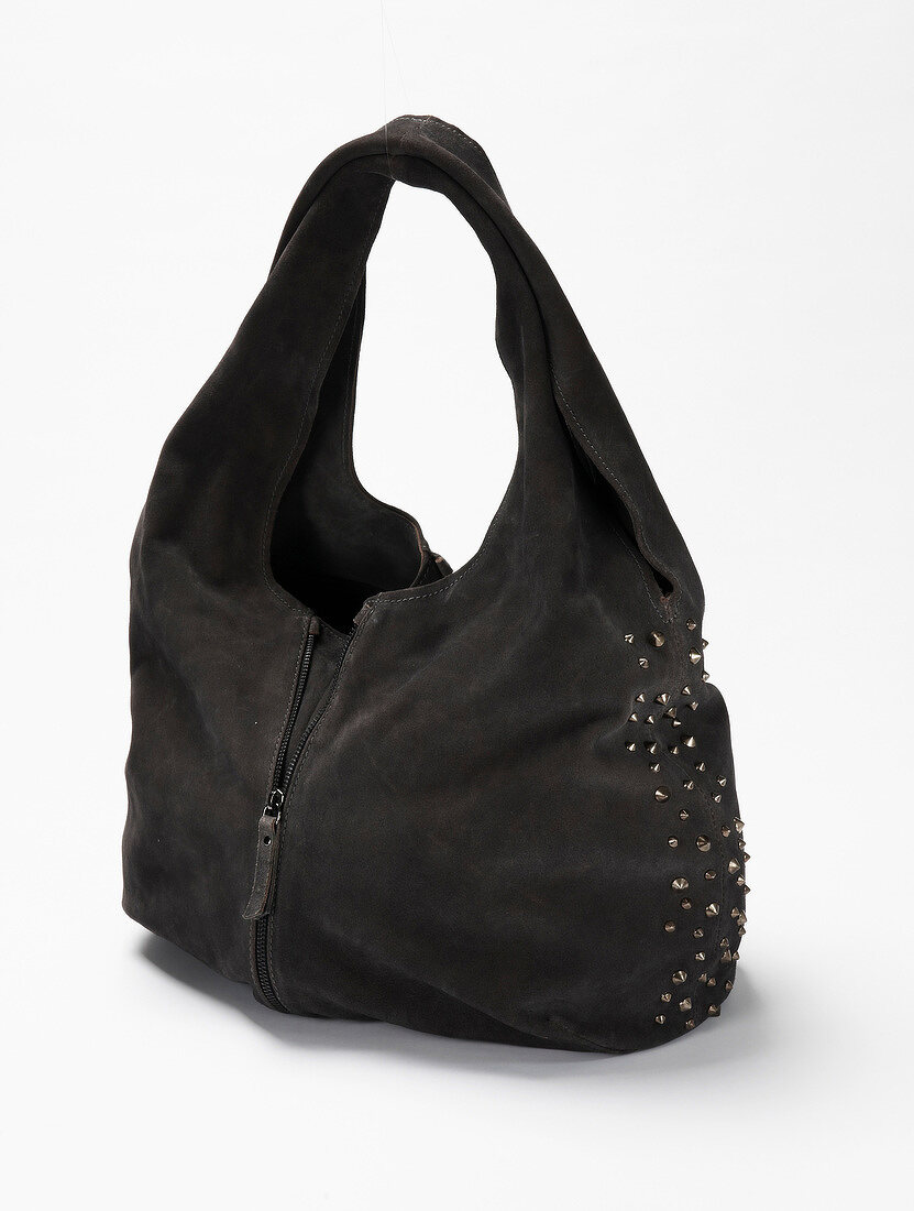 Close-up of black suede leather handbag with rivets on white background