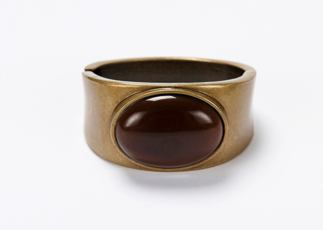 Close-up of golden bangle with cat eye stone on white background