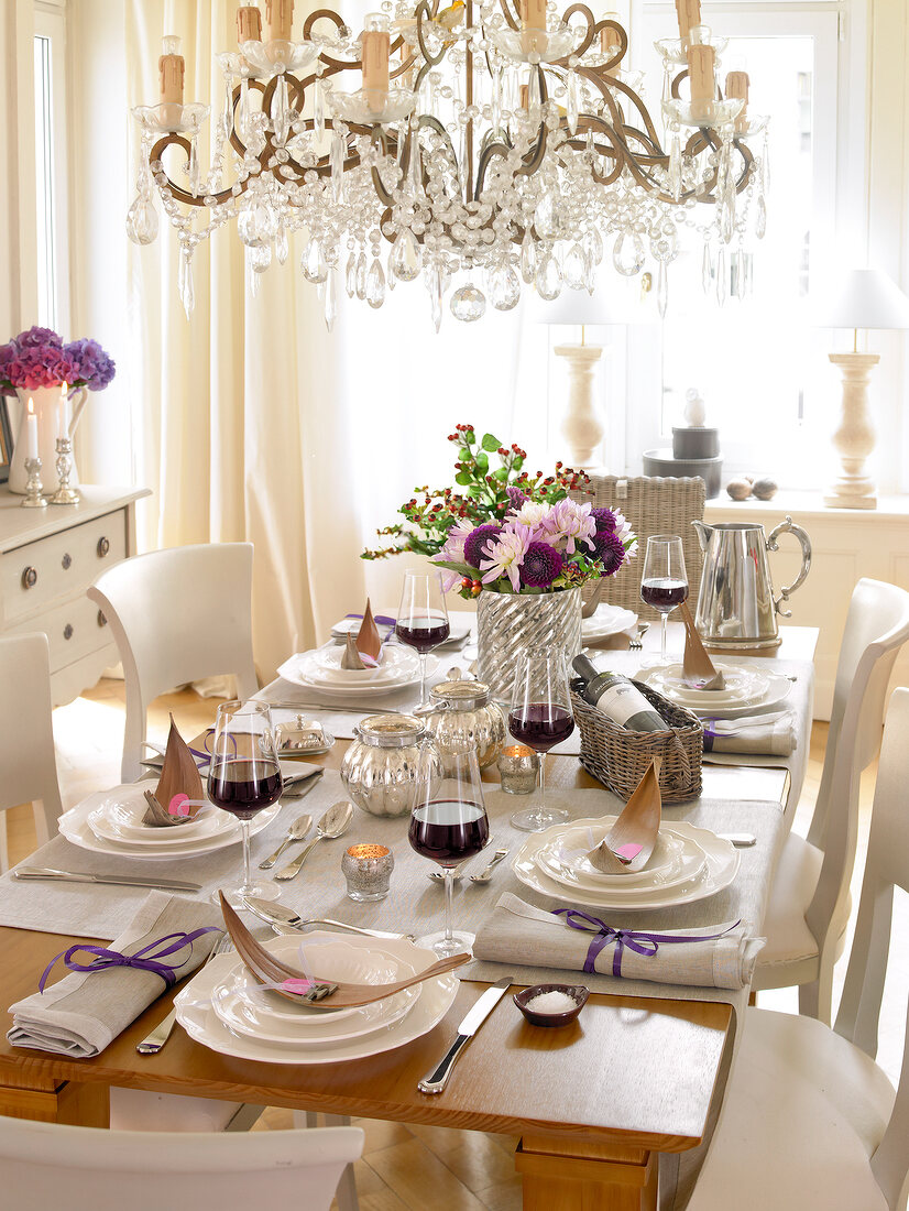 Festively decorated table with champagne glass, plates and chandeliers