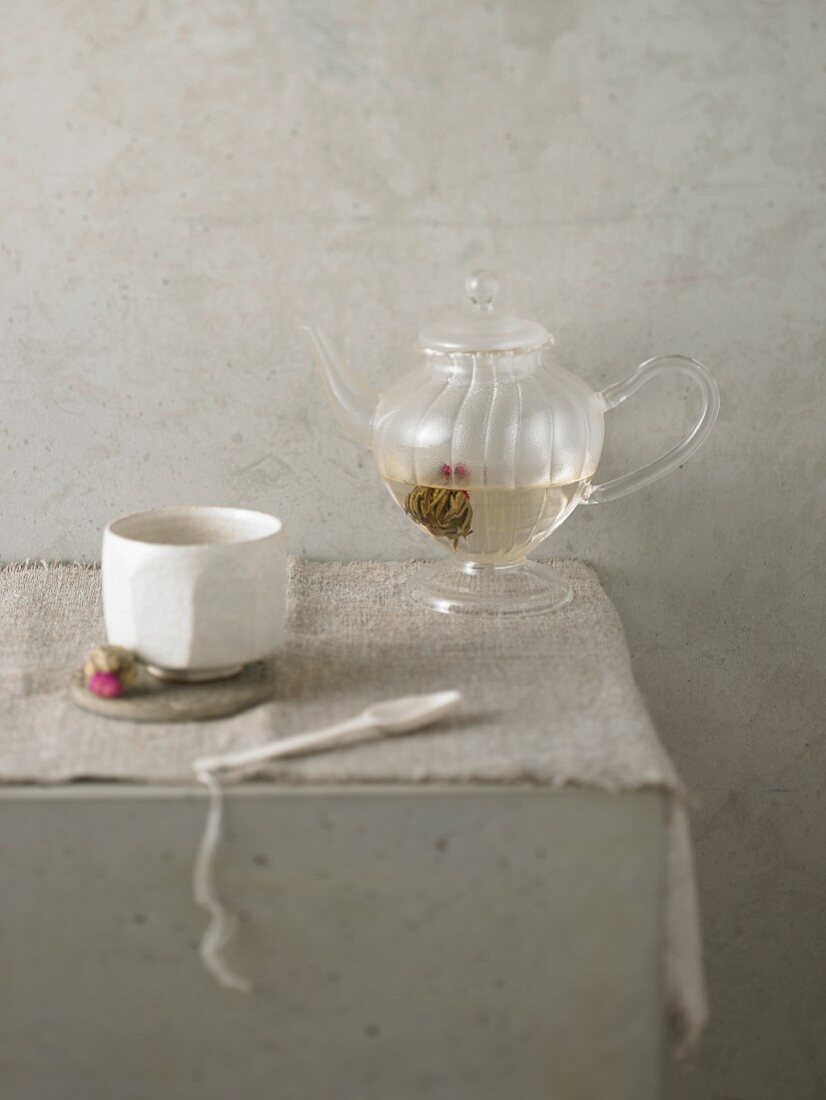 An arrangement with a tea bowl and flowering tea in a glass teapot