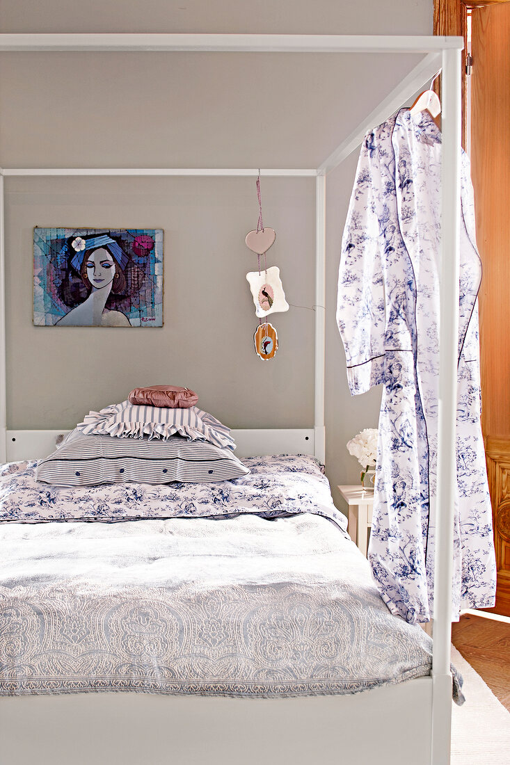 View of modern four poster bed with curtain and modern abstract painting and wall hanging