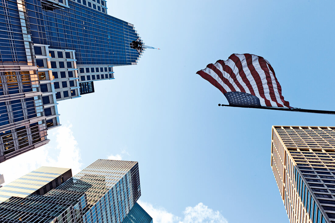 Low angle view of American flag waving on skyscrapers in New York, USA