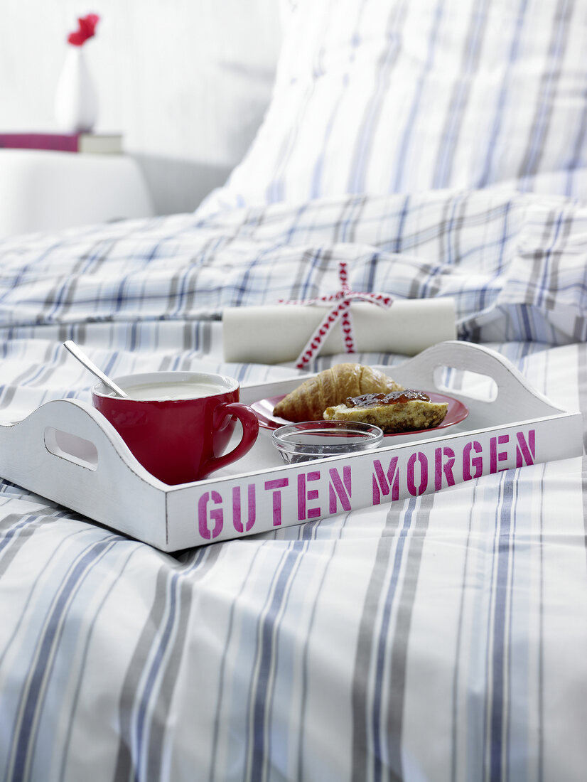 Frühstück am Bett: Tablett mit Tasse und Teller mit Brötchen