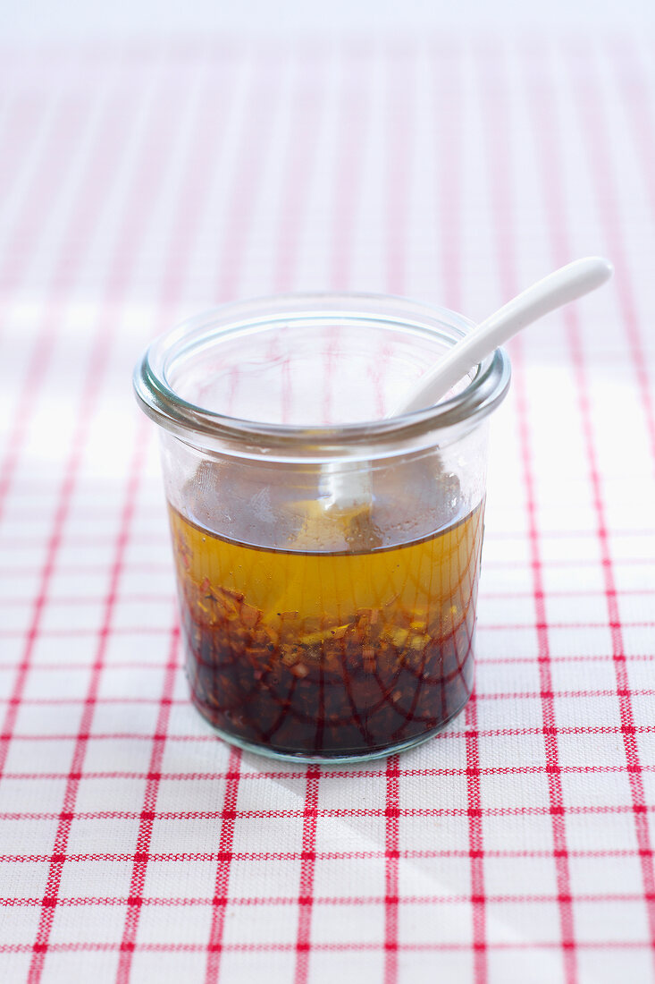 Vinaigrette in glass jar with spoon on checked tablecloth