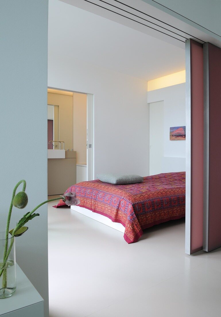 View of bedroom with bed, sliding pink door and illuminated light