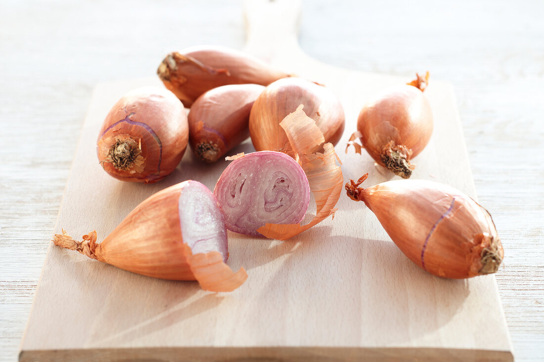 Several whole and halved shallots on cutting board