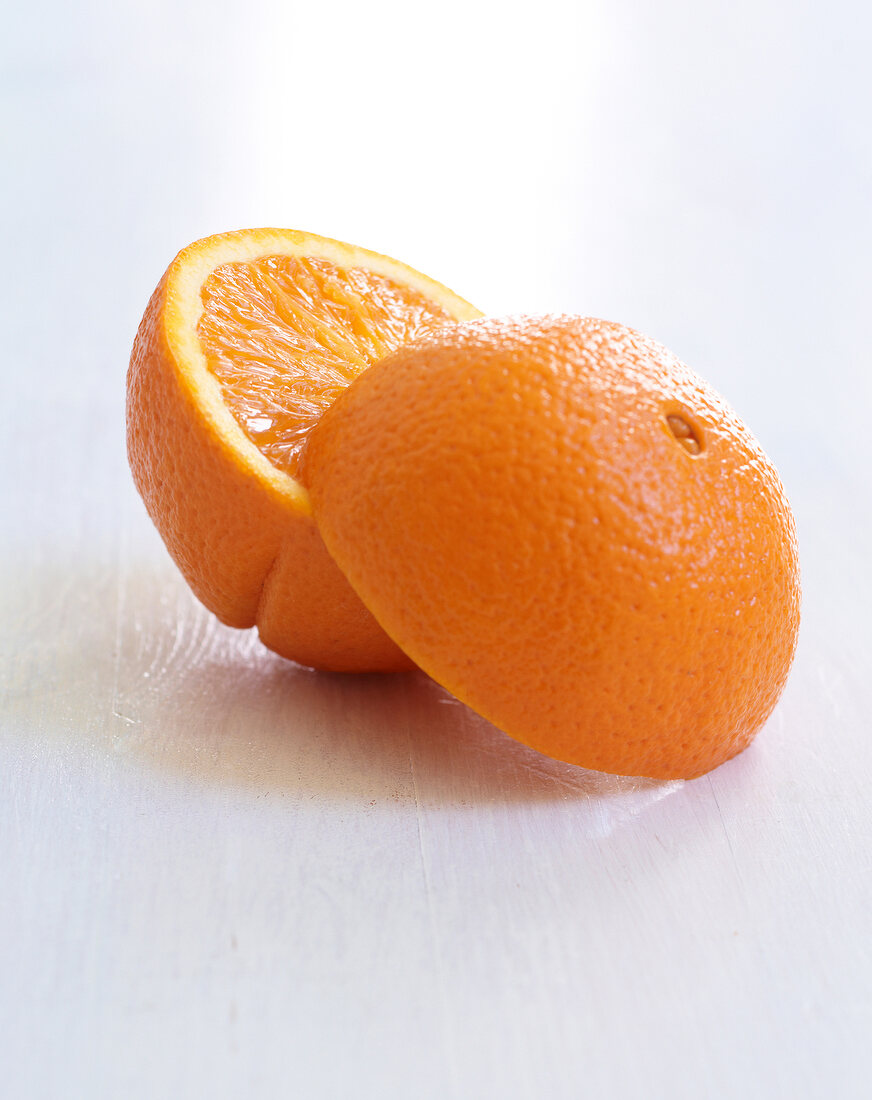 Close-up of two whole and two halved oranges on white background