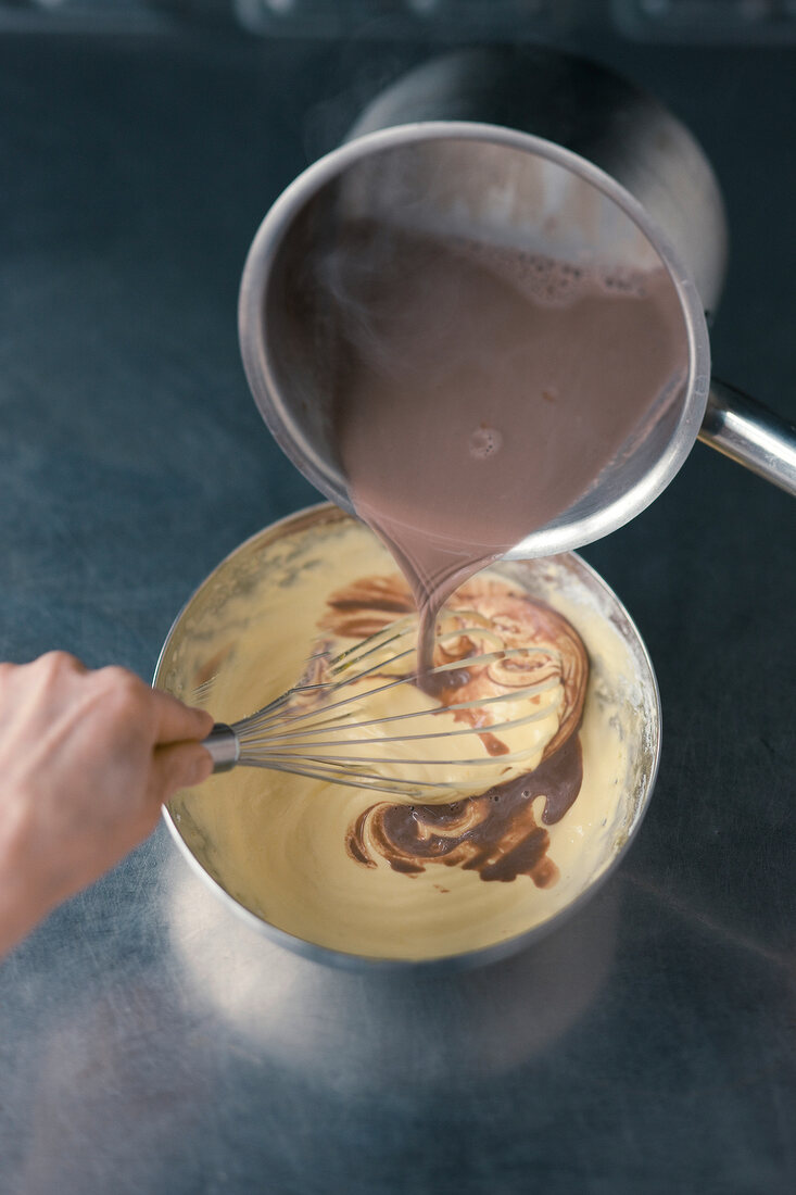 Close-up of mixing liquid chocolate to souffle batter with whisk