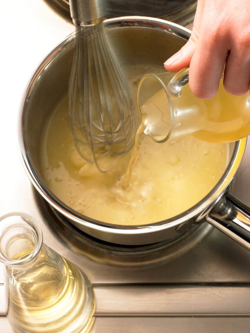 Adding liquid to mixture in saucepan while preparing mustard sauce, step 2