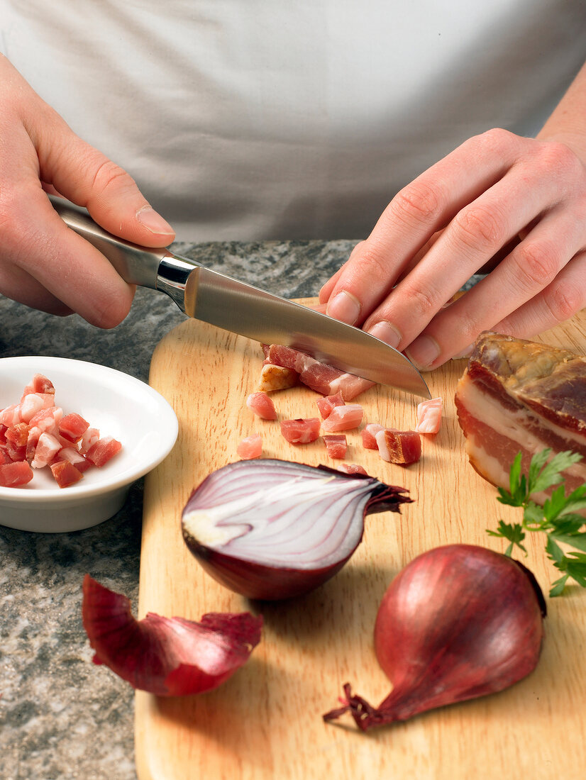 Bacon being cut into small pieces on cutting board while preparing bacon sauce, step 1