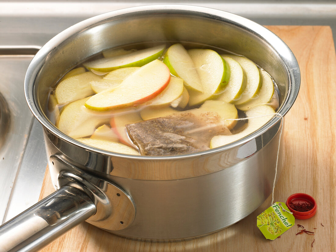 Slices of apple and tea bag in saucepan for preparation of apple soup, step 2