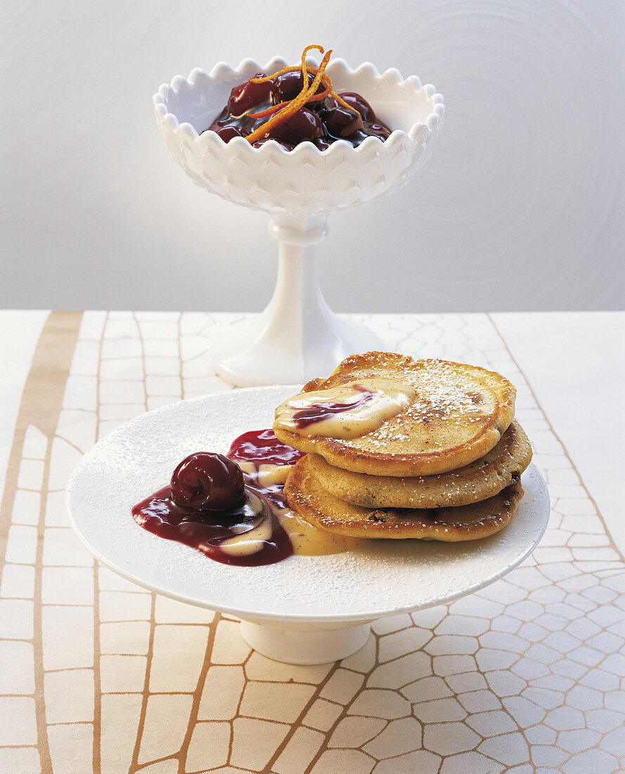 Sour cream pancakes with cherries and vanilla sauce on cake stand