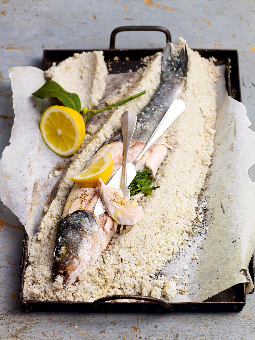 Sea bass in salt crust with lemon in serving tray