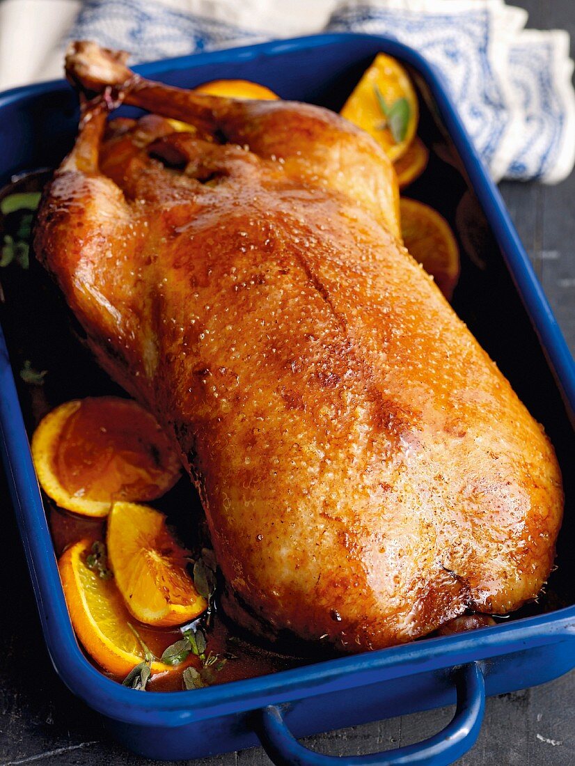 Stuffed roast duck with fresh marjoram in a roasting tin