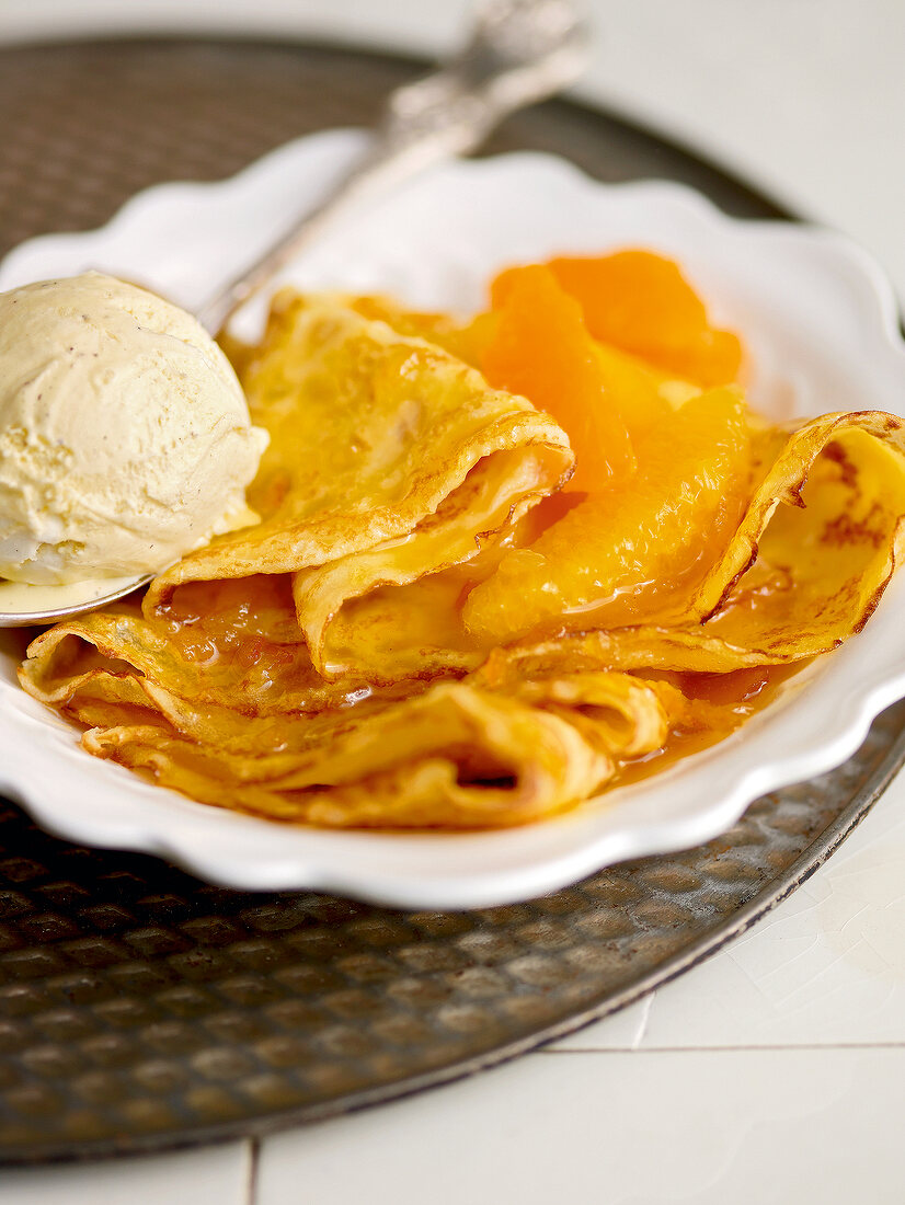 Close-up of crepes suzette with orange mandarin and vanilla ice cream on plate